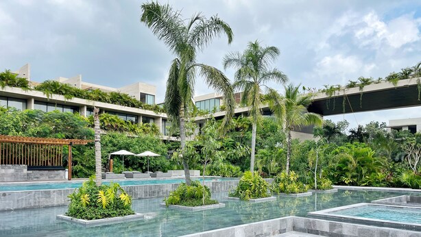 A modern hotel pool area with multiple swimming pools, surrounded by lush greenery and palm trees. - Mistiq Tulum (Tulum)