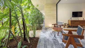 A modern interior with a stone pathway leading to a seating area, surrounded by lush greenery. - Mistiq Tulum (Tulum)