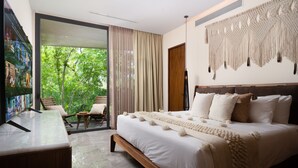 A modern bedroom with a large bed, a desk, and a view of greenery through the glass door. - Mistiq Tulum (Tulum)