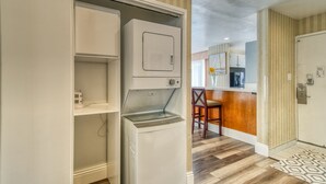 Een compacte keuken met een ingebouwde wasmachine en droger, een houten bartop en een getextureerd vloerkleed.