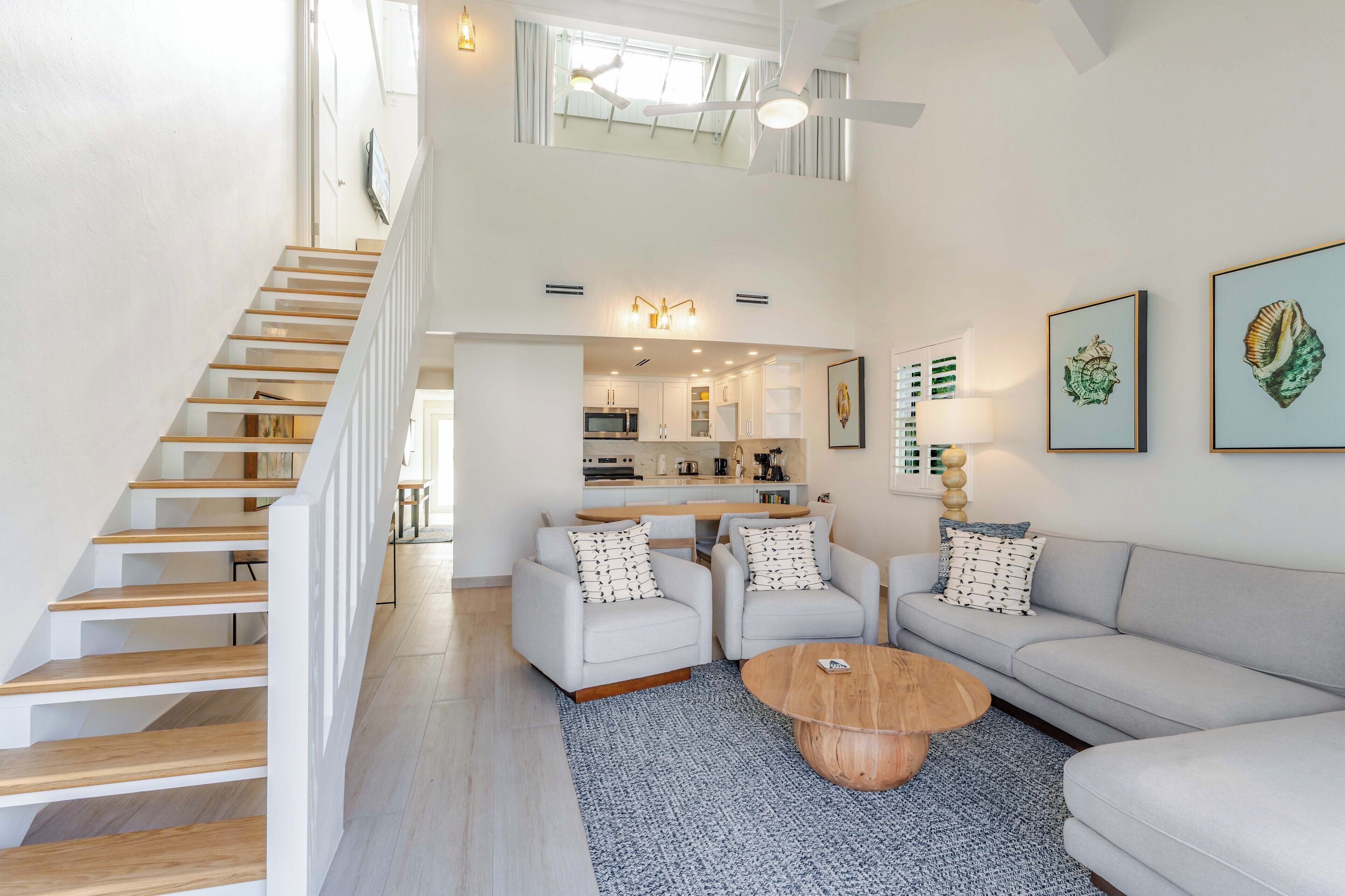 A modern living room with a staircase, a sofa set, a coffee table, and artwork on the walls.