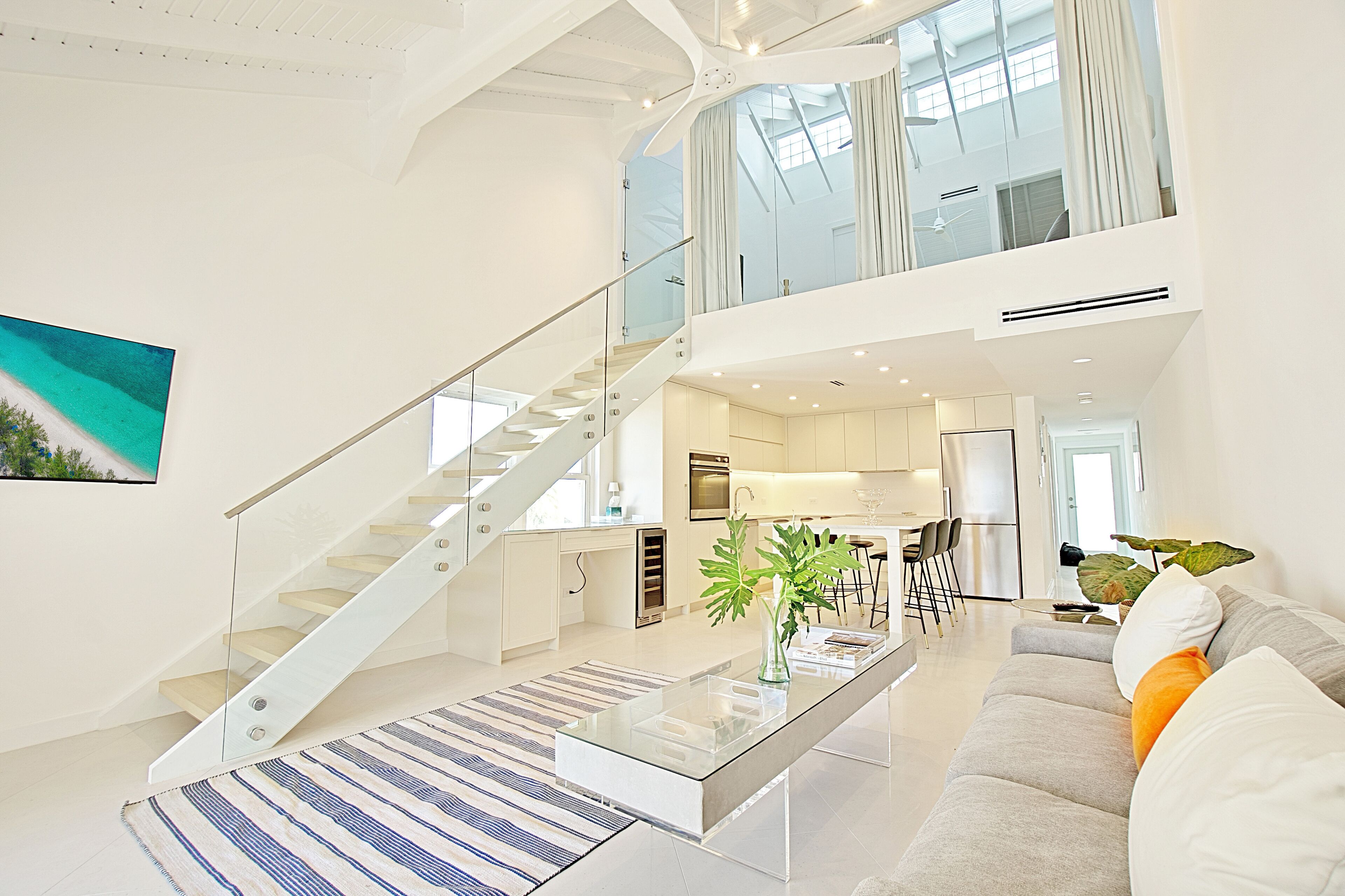 Un intérieur moderne avec un escalier menant à une mezzanine, une cuisine et un coin salon avec une table basse.