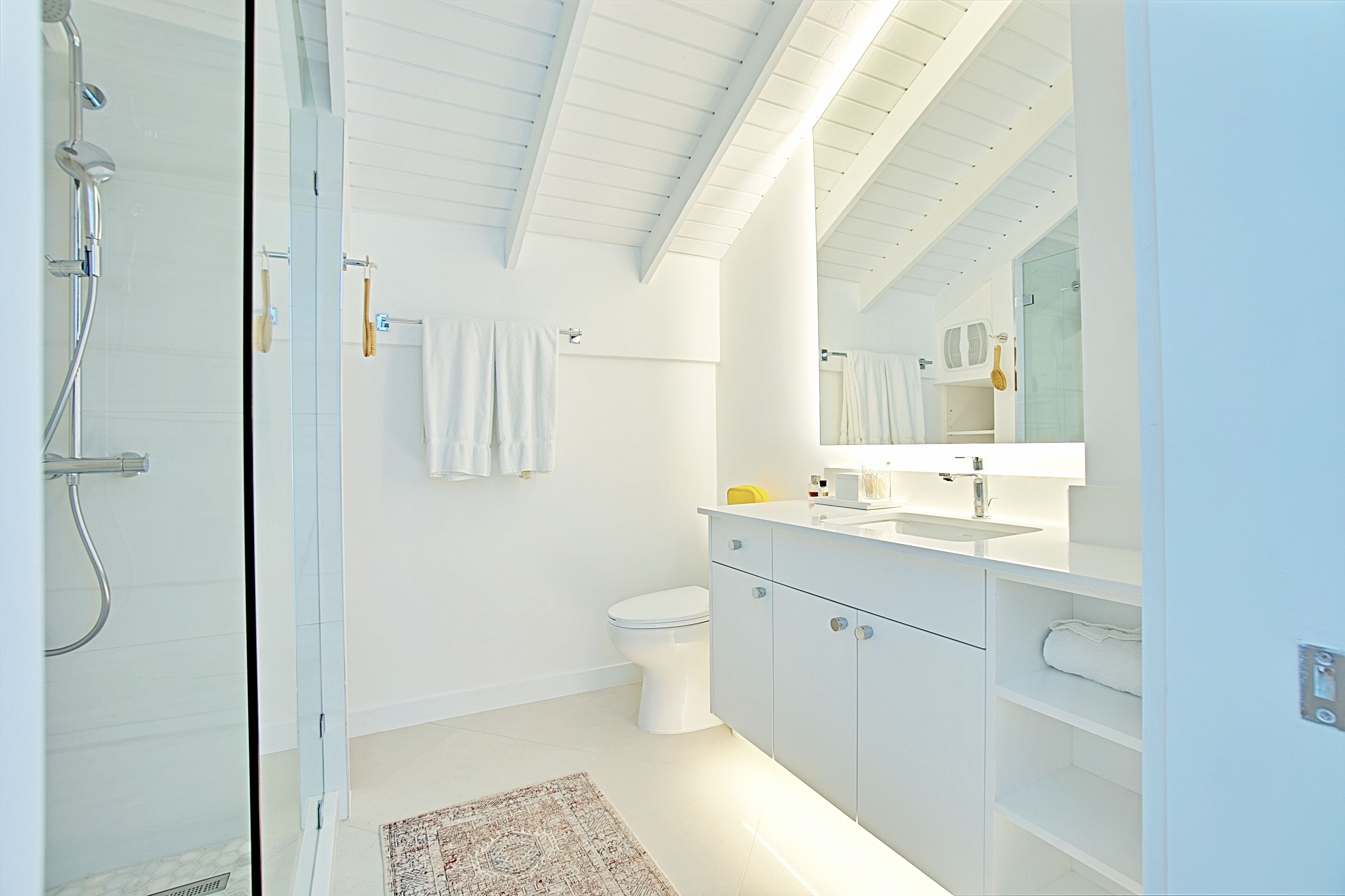 A modern bathroom with a glass shower enclosure, a white toilet, and a vanity with a mirror.