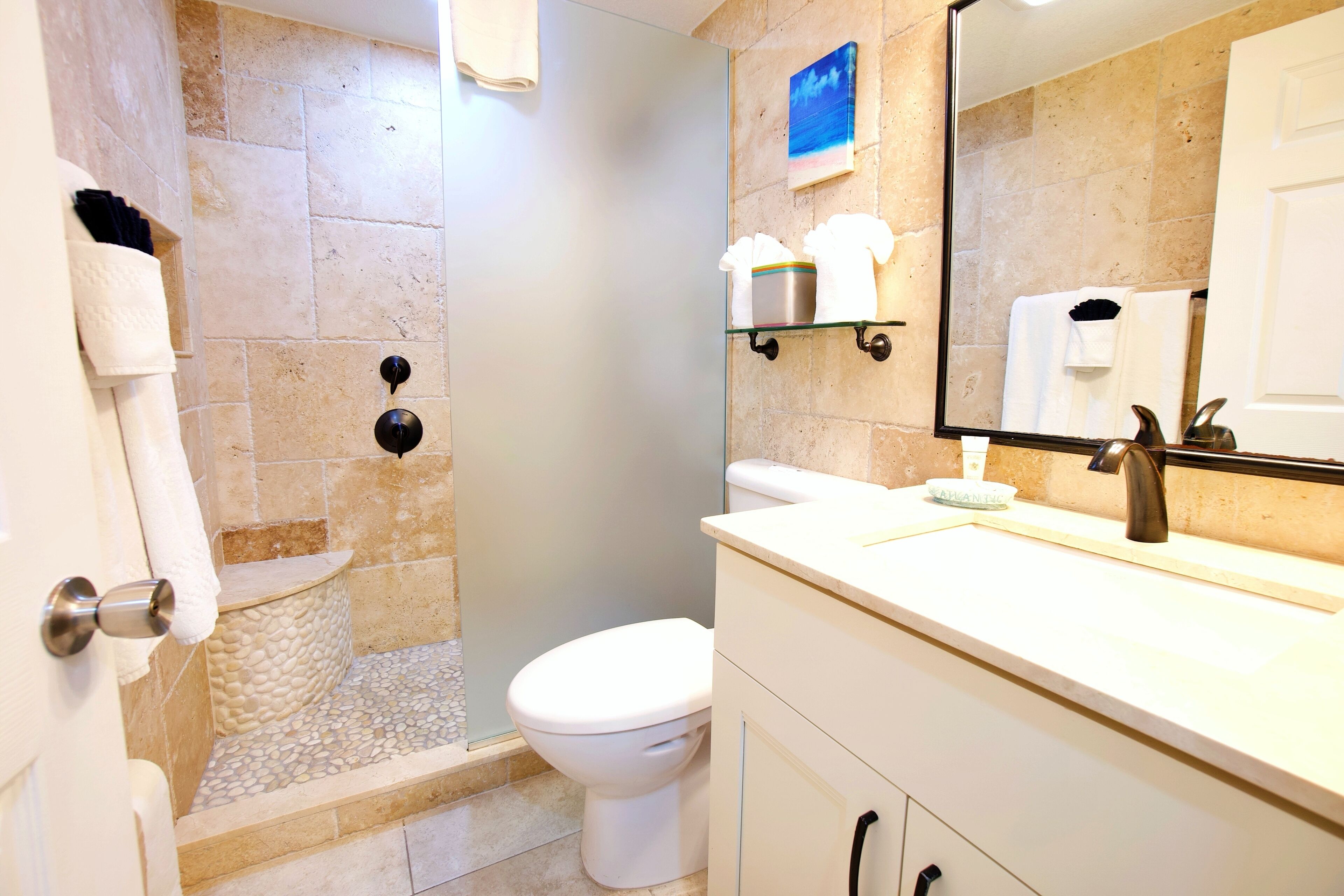 A bathroom with a glass-enclosed shower, a white toilet, and a vanity with a mirror.