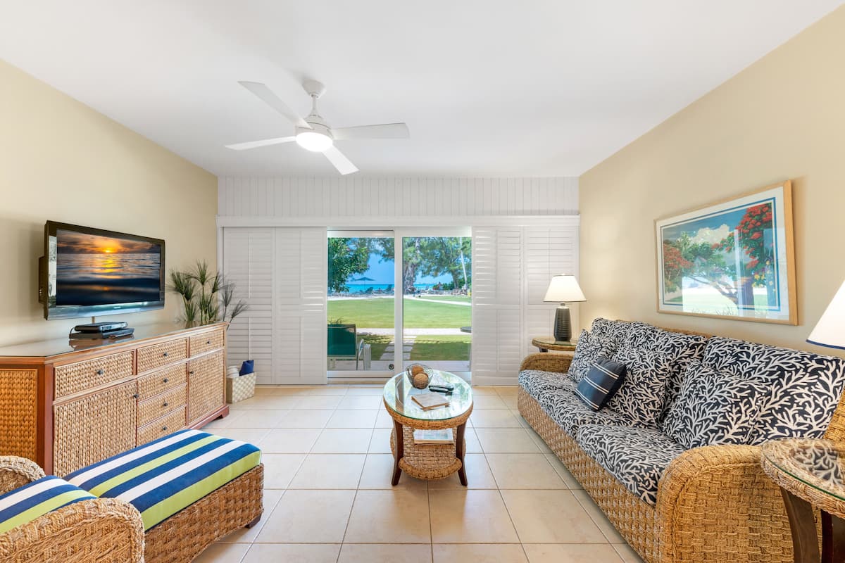 Un salon spacieux doté d’une grande fenêtre, d’un ventilateur de plafond, d’un téléviseur, d’un canapé et d’une table basse.