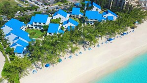Vue aérienne d’un complexe hôtelier comprenant plusieurs bâtiments, une plage et un océan d’un bleu limpide.