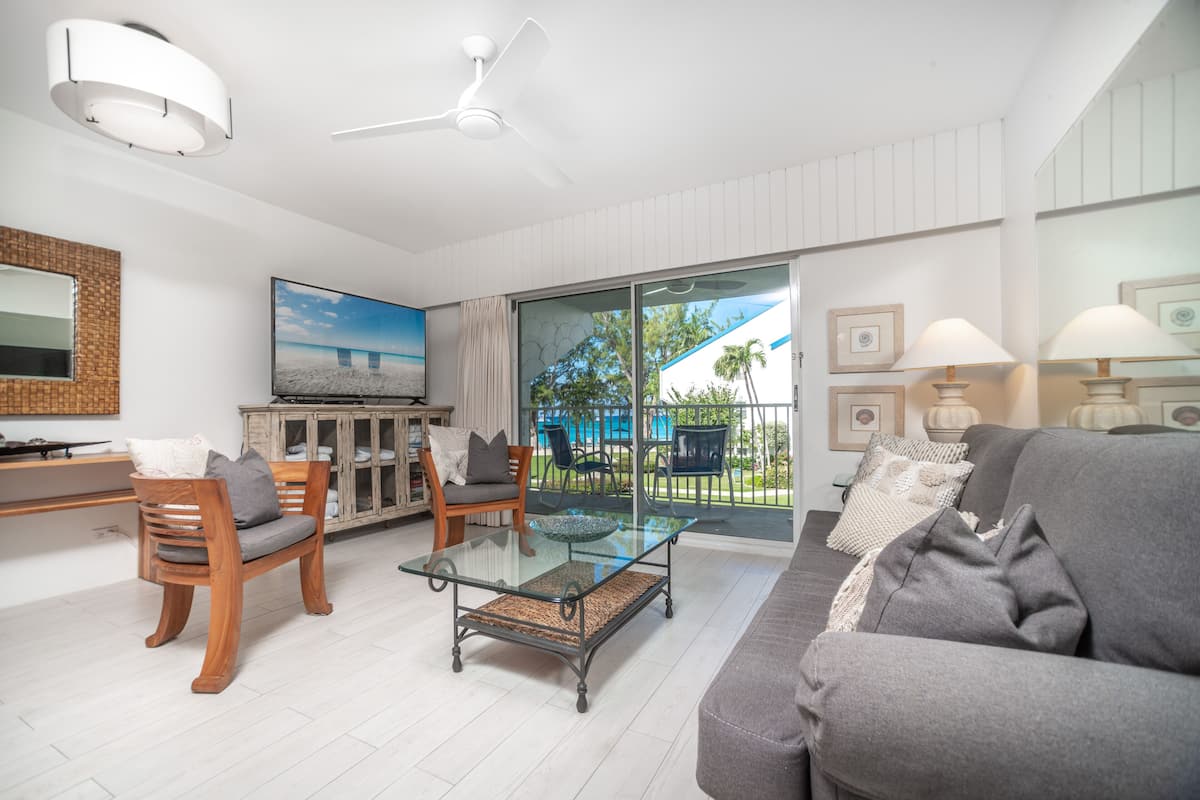 Un salon moderne avec une table basse en verre, des meubles en bois, un téléviseur à écran plat et un balcon avec vue.