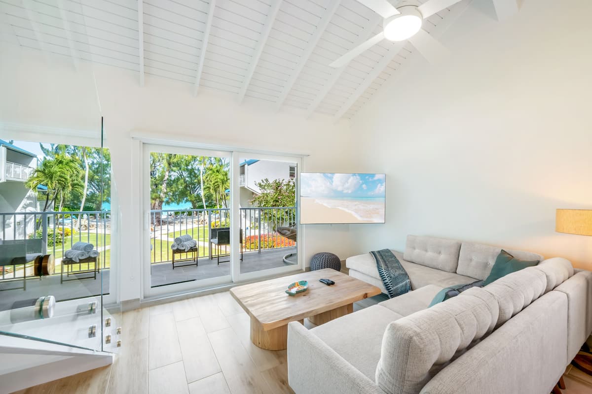 Un salon moderne avec un canapé, une table basse et une grande fenêtre donnant sur un balcon.