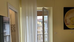 A room with a sliding glass door leading to an outdoor balcony, a sofa, and a painting on the wall. - Alfredo's Room Central Station (Milano)