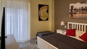 A bedroom with a bed, a nightstand, a lamp, a painting, and a window with curtains. - Alfredo's Room Central Station (Milano)