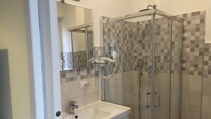 A modern bathroom with a glass-enclosed shower, a white sink, and a tiled backsplash. - Alfredo's Room Central Station (Milano)
