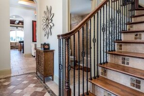 Staircase leads to an upper floor, featuring a decorative wall piece above and a wooden cabinet to the left.