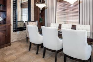 Enjoy meals in this dining area with a rectangular table and four chairs, set with a tablecloth, under a fan-shaped light fixture.