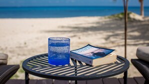 A round table with a book and a glass on it, set against a beach backdrop. - Beach house w/ private pool & sandy beach for 8 (San Miguel de Cozumel)