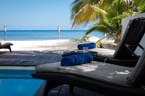 A poolside lounge chair with a cushion and a rolled towel, overlooking a beach and the ocean. - Beach house w/ private pool & sandy beach for 8 (San Miguel de Cozumel)