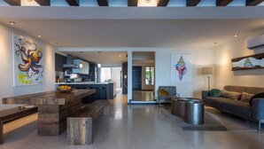 A modern living room with a wooden coffee table, a sofa, and a dining area with a kitchen in the background. - Beach house w/ private pool & sandy beach for 8 (San Miguel de Cozumel)
