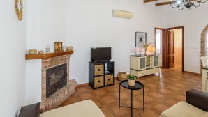A living room with a fireplace, a television, a cabinet with baskets, and a dining area with a table and chairs.