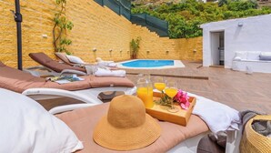A poolside area with lounge chairs, a pool, and a tray with drinks and flowers.