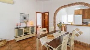 A dining area with a wooden table, white chairs, and a buffet cabinet.