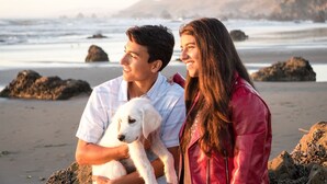 A beach scene with two people holding a puppy, with rocks and the ocean in the background. - Sundog Cottage - Clean & Cozy - EV - Walk to Food & Beach - Fenced Yard for Dog (Dillon Beach)