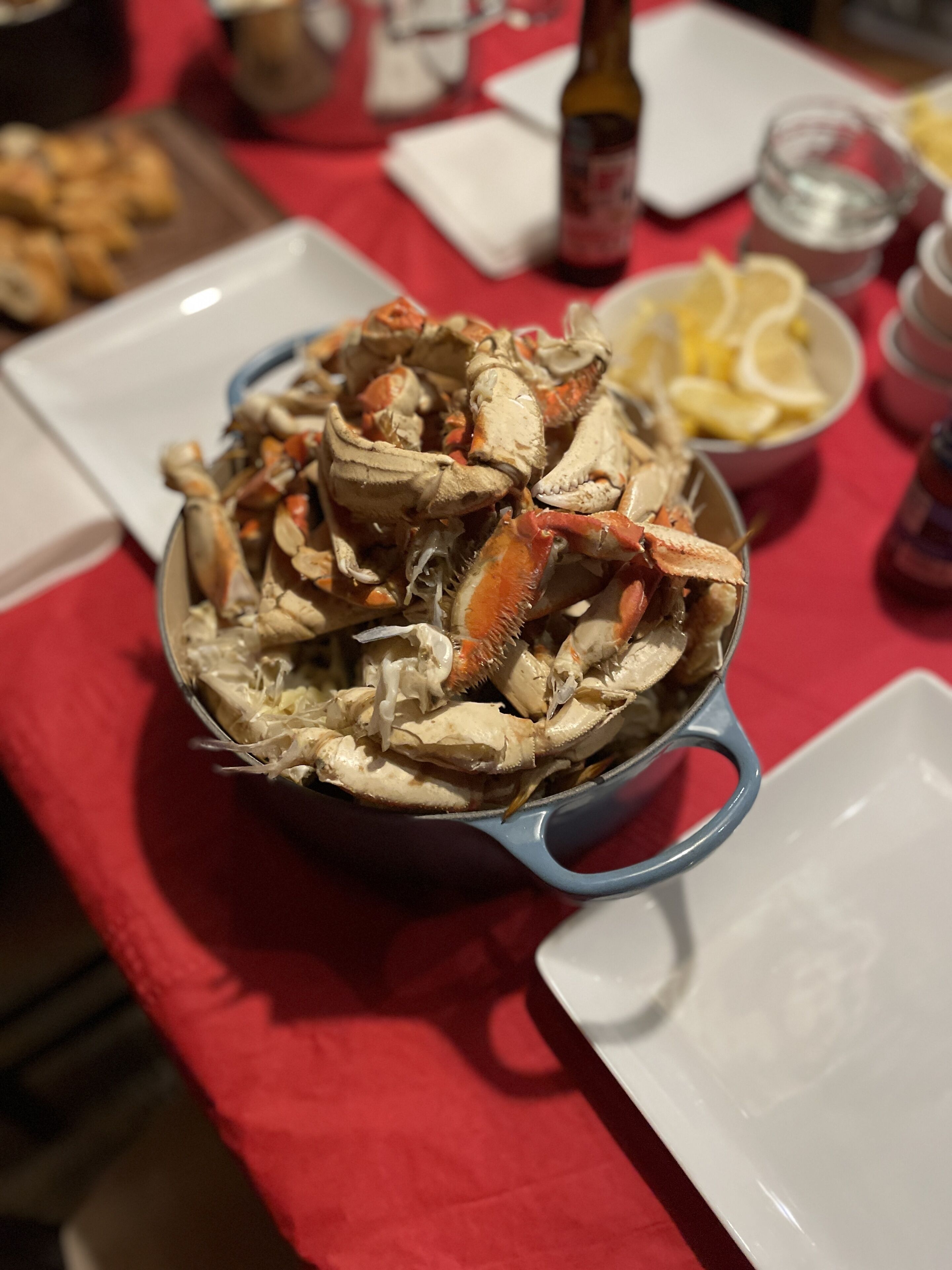A table with a blue bowl filled with crab, lemon wedges, and a bottle of sauce.