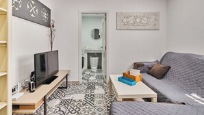 Un salon moderne avec un téléviseur, un canapé et des carreaux de sol à motifs.