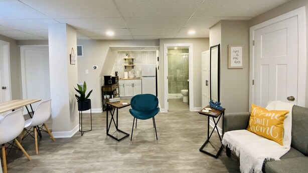 A modern living room with a sofa, a teal chair, and a dining area with a table and chairs. - Charming 2 Bedroom Apt. Close to Valparaiso University Short-Term Stays (Valparaiso)