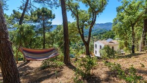 A rustic house surrounded by trees, a hammock, and a clear view of the landscape. - Casa Rural Monte Dios Jubrique by Ruralidays (Málaga)