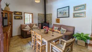A cozy living room with a wooden dining table, two sofas, and a fireplace. - Casa Rural Monte Dios Jubrique by Ruralidays (Málaga)