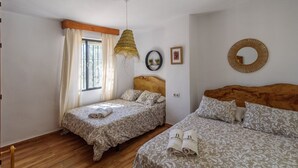 A bedroom with two beds, a window with curtains, a hanging light fixture, and a round mirror on the wall. - Casa Rural Monte Dios Jubrique by Ruralidays (Málaga)