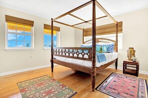 A four-poster bed with a wooden frame, a small bedside table with a lamp, and a patterned rug on the floor.