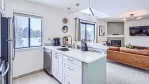 A modern kitchen with a dishwasher, sink, and a dining area with a sofa.