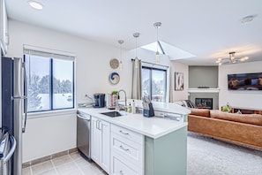 A modern kitchen with a dishwasher, sink, and a dining area with a sofa.