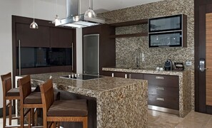 Une cuisine moderne dotée de plans de travail en granit, d’appareils électroménagers en acier inoxydable et d’un téléviseur encastré.