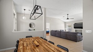 Eine moderne Küche mit einem Holzes Esstisch, schwarzen Stühlen, Pendelleuchten und einem eingebauten Backofen.