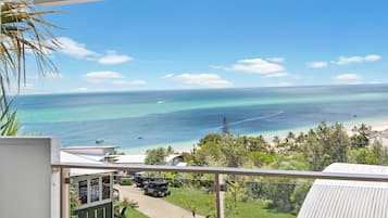Enjoy unobstructed ocean views from the balcony of this beachfront property, surrounded by lush greenery and a well-maintained lawn.
