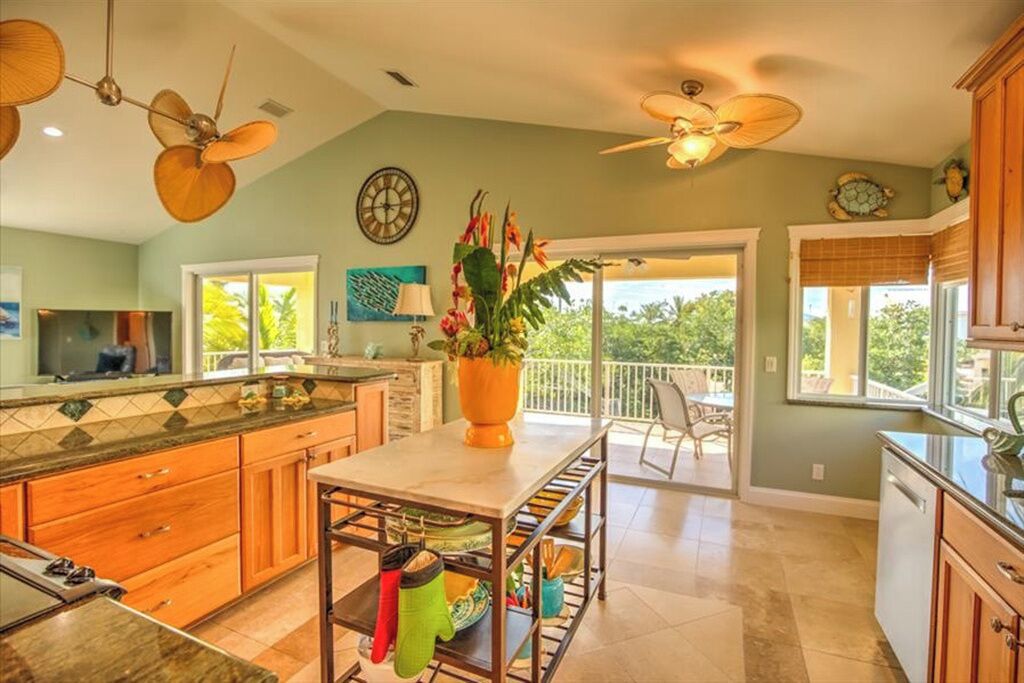 A spacious kitchen with wooden cabinets, a central island, and a dining area with a view to the outdoors.