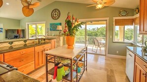 Una cocina amplia con armarios de madera, una isla central y un comedor con vistas al exterior.