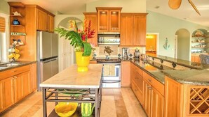 Una cocina con armarios de madera, una isla central y un ventilador de techo.