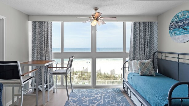 A room with a bed, a desk, a chair, and a view of the beach. - ☀️Edgewater West 34. stocked poolside storage room.  New paint and floors!!⛱️ (Gulf Shores)