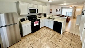 Una cocina moderna con gabinetes blancos, un refrigerador de acero inoxidable, una estufa negra y un lavavajillas.