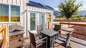 A deck with a grill, dining table, and chairs, overlooking a mountainous landscape. - Zion-Day-Trip Ready • Tiny Home + Mountain Views (Apple Valley)