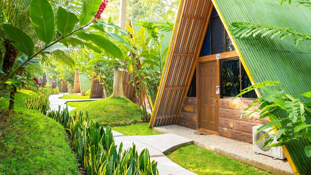 Un bâtiment de style tropical, doté d’un toit en pente, d’une porte en bois et d’un petit appareil de climatisation.