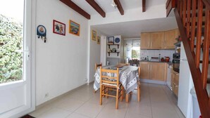 Une cuisine spacieuse avec des meubles en bois, un coin repas comprenant une table et des chaises, et un escalier menant à un autre niveau.
