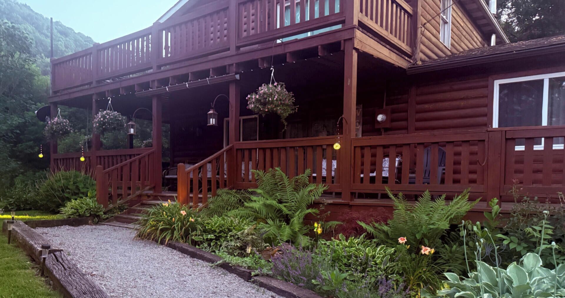 Une cabane en bois avec une véranda, un éclairage extérieur et un jardin.