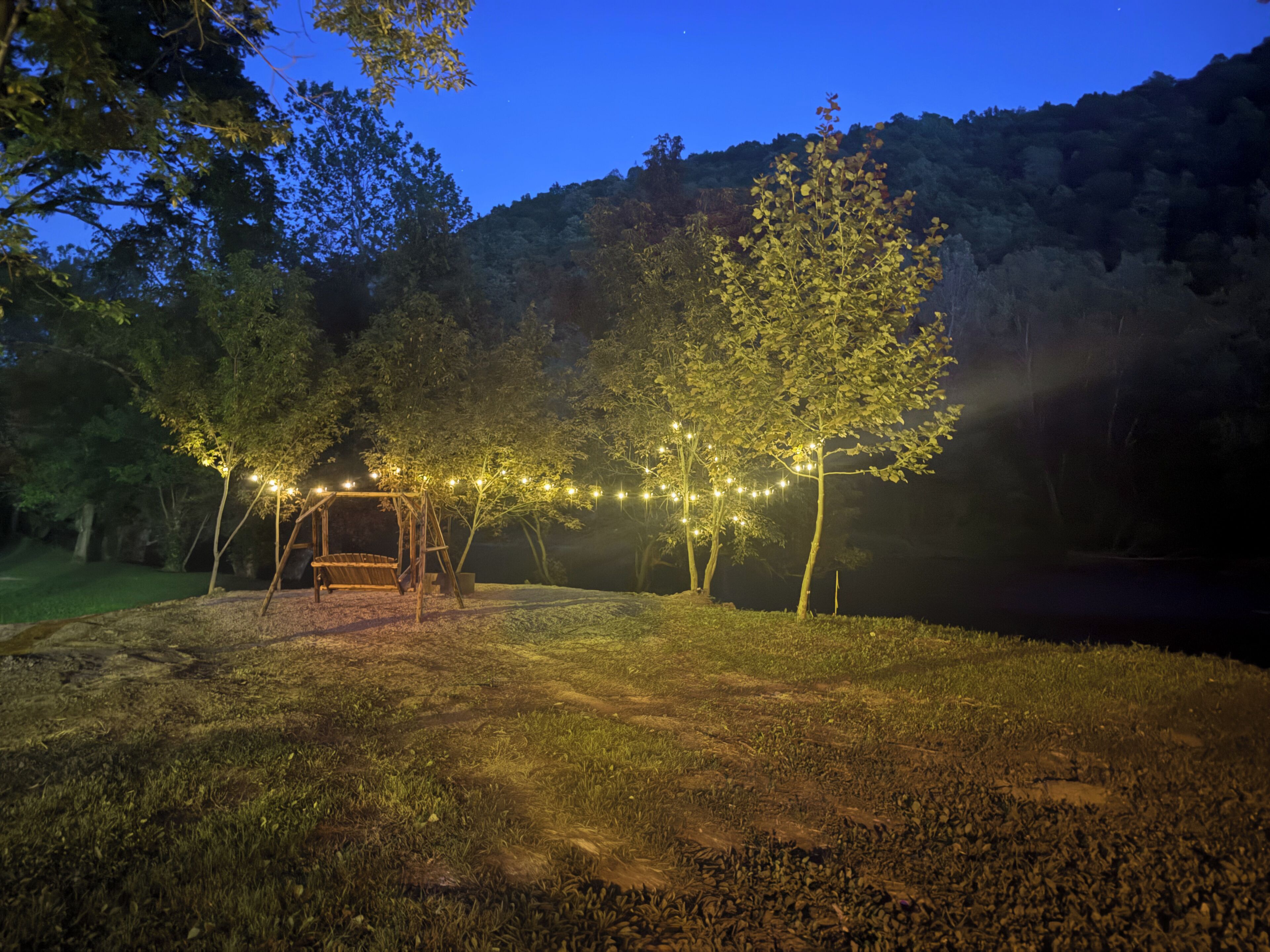 A nighttime outdoor area with a swing set and string lights.