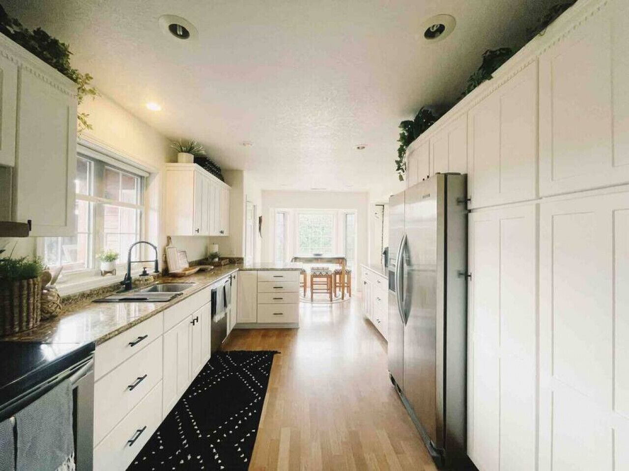 Una cocina moderna con armarios blancos, una isla central y vistas al comedor.