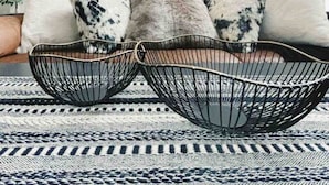 En moderne stue med sofa, to hængende lamper og et mønstret tæppe.