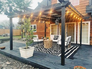 A wooden deck with outdoor seating, string lights, and a potted plant.