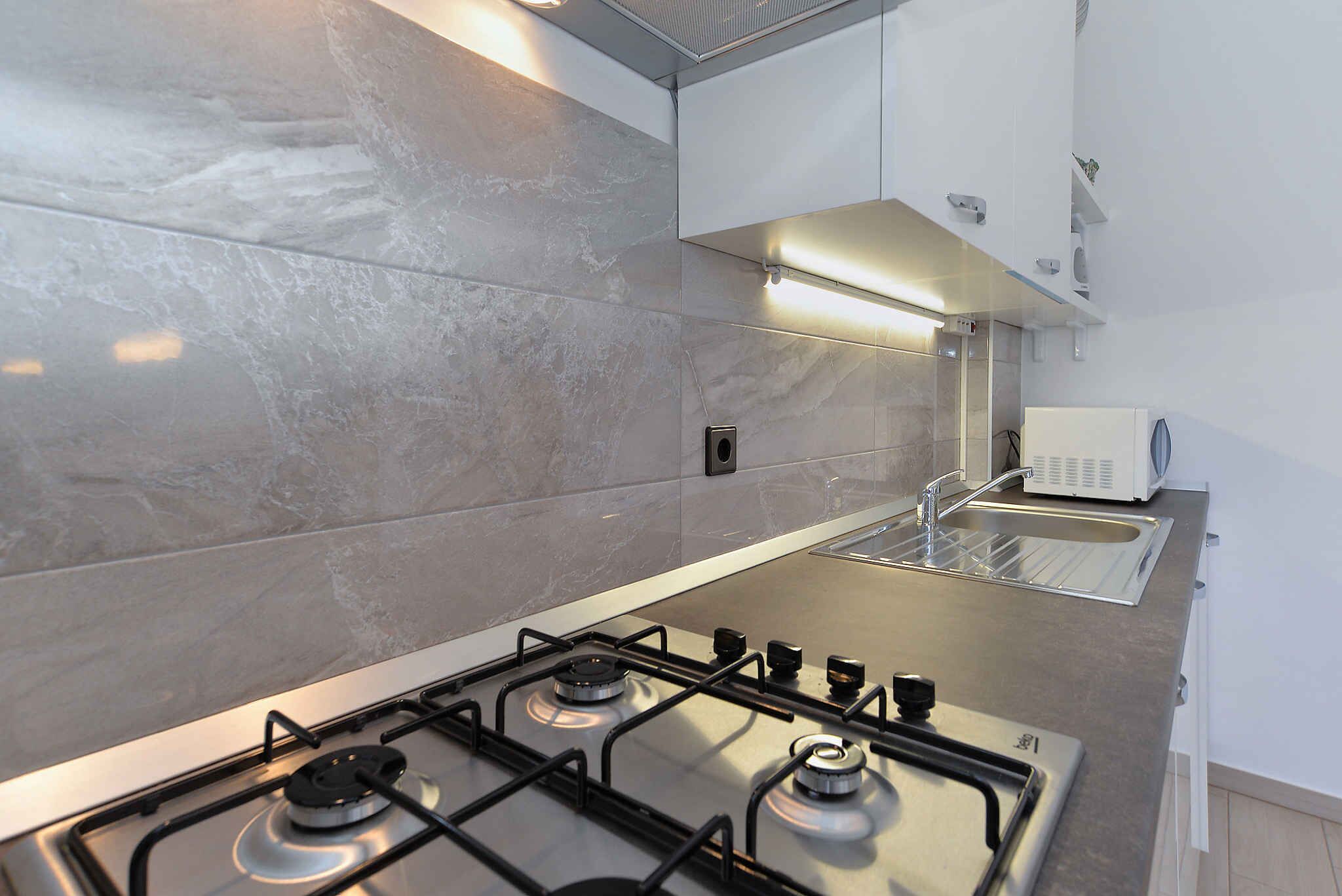 Une cuisine moderne équipée d’une cuisinière à gaz, de plans de travail en acier inoxydable et d’un four encastré.